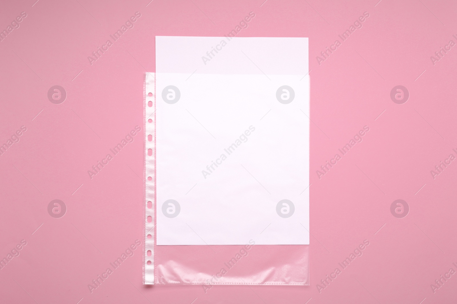 Photo of Punched pocket with paper sheet on pink background, top view. Space for text