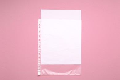 Photo of Punched pocket with paper sheet on pink background, top view. Space for text