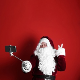 Authentic Santa Claus taking selfie on red background