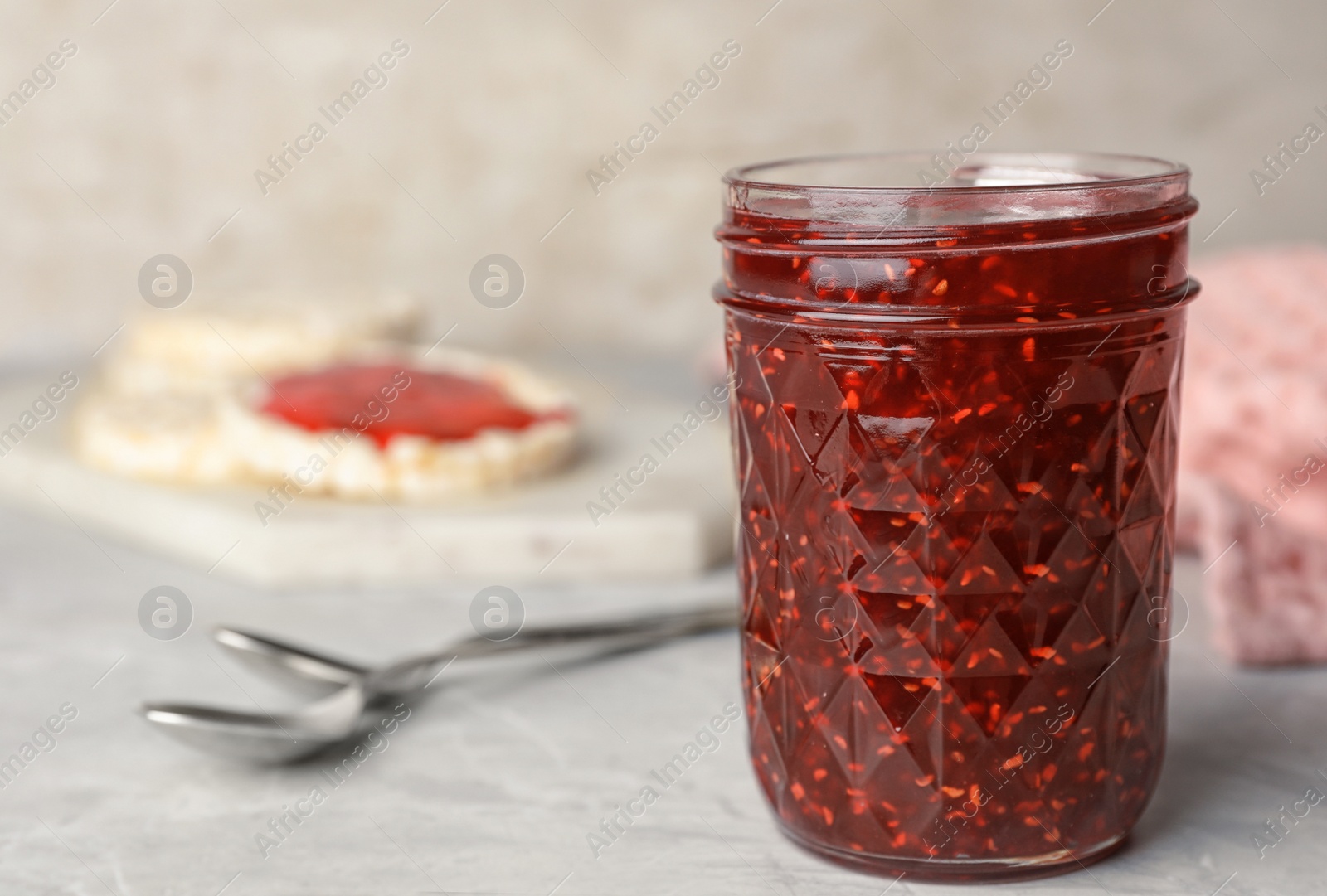Photo of Homemade delicious raspberry jam on marble table