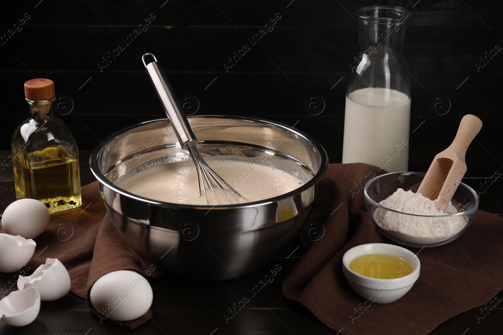 Photo of Composition with whisk and dough in bowl on wooden table