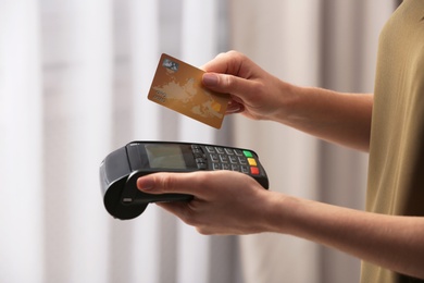 Woman using modern payment terminal indoors, closeup