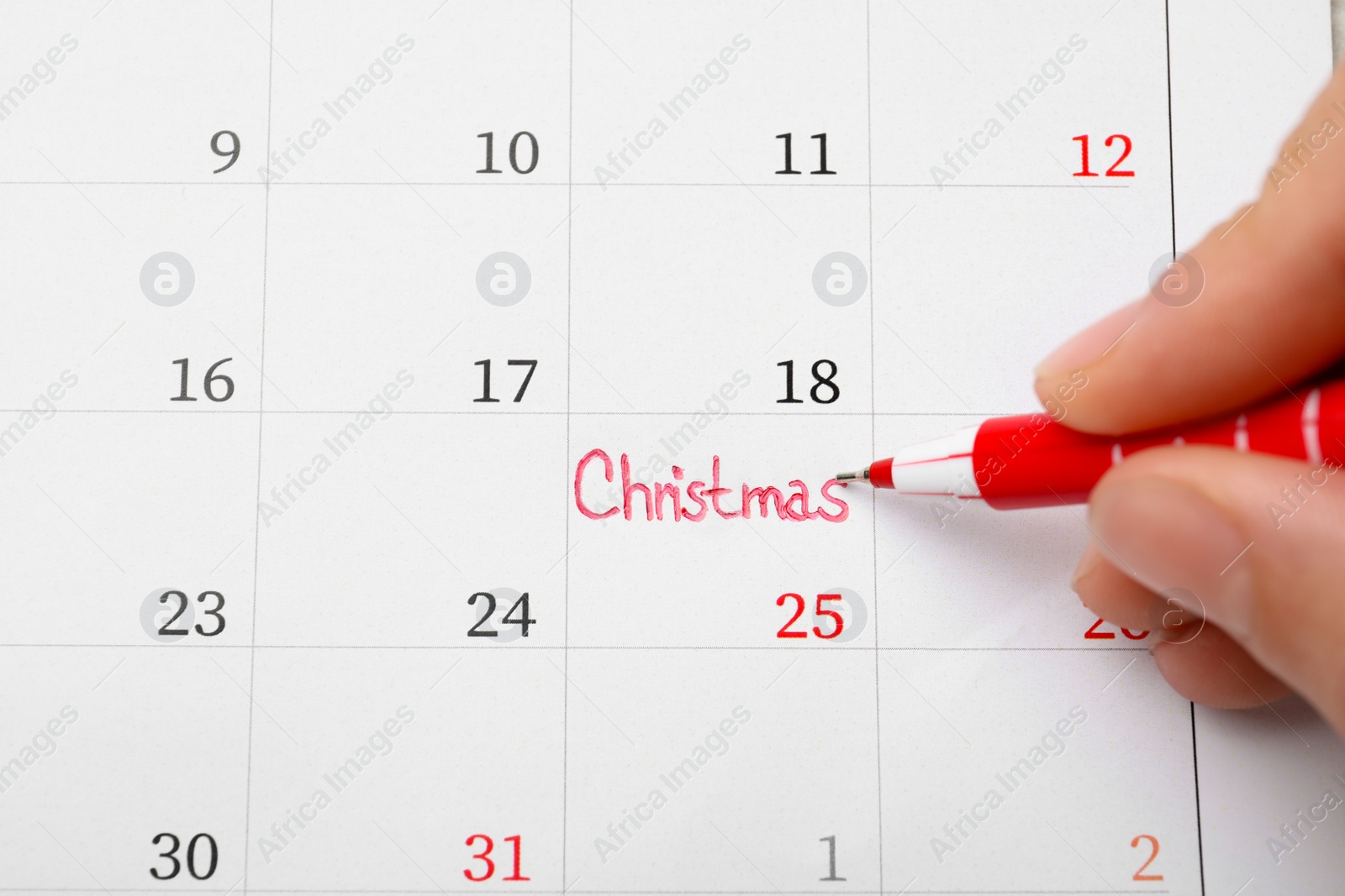 Photo of Woman writing word Christmas on calendar, top view. Holiday countdown