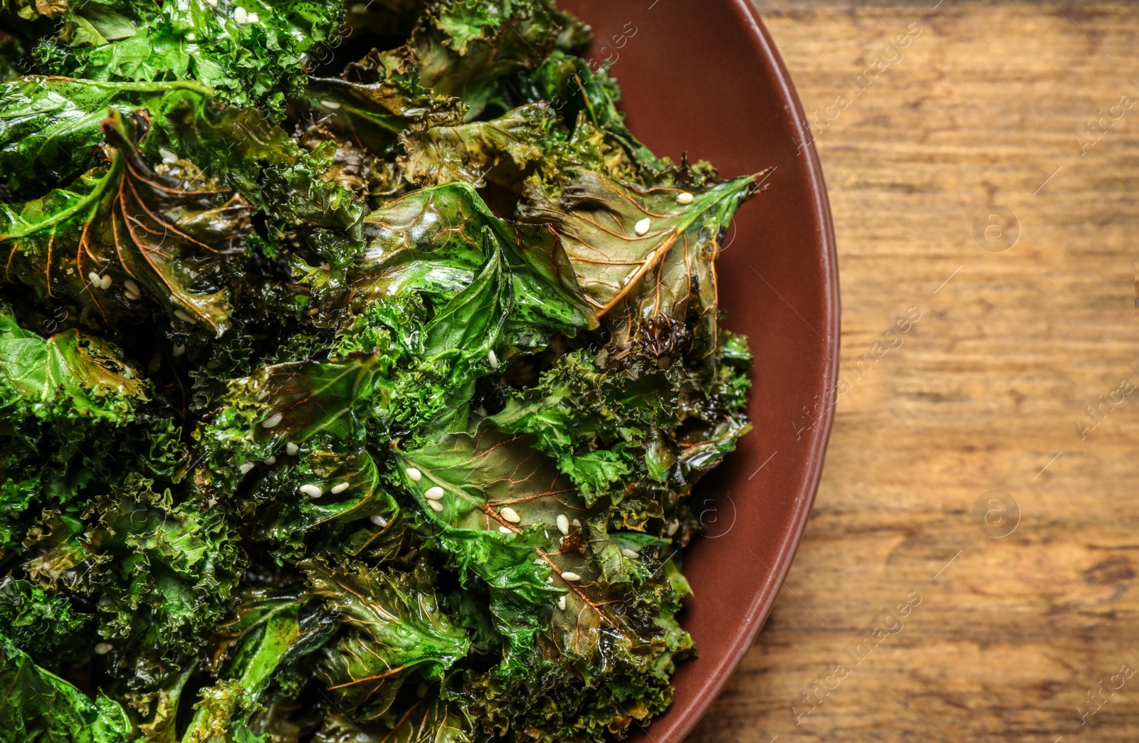 Photo of Tasty baked kale chips on wooden table, top view