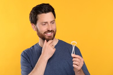Photo of Happy man with tongue cleaner on yellow background. Space for text