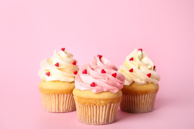 Photo of Tasty cupcakes with heart shaped sprinkles for Valentine's Day on pink background