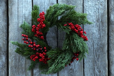 Photo of Beautiful Christmas wreath with red berries hanging on wooden wall
