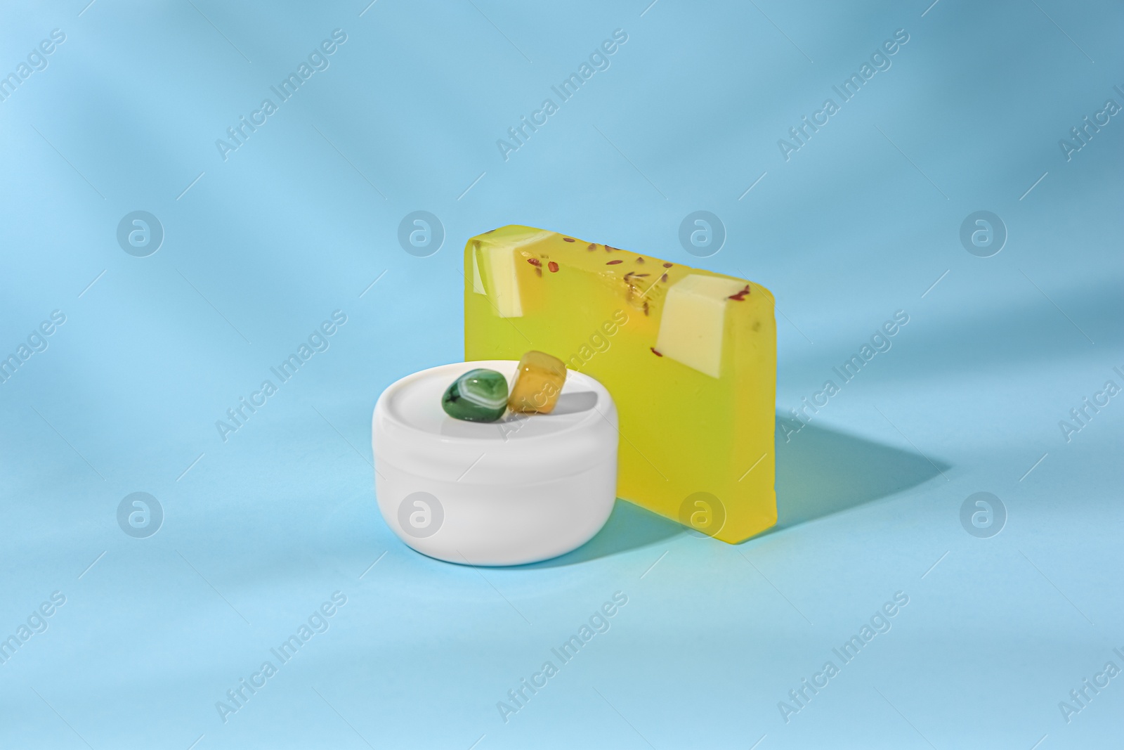 Photo of Cosmetic products and precious gemstones on light blue background