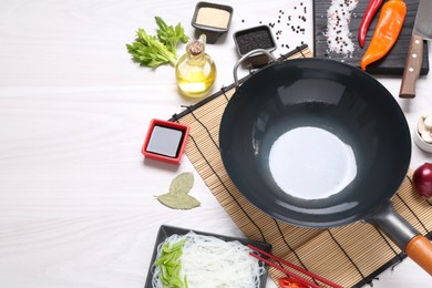 Photo of Wok, chopsticks and different products on white wooden table, above view. Space for text