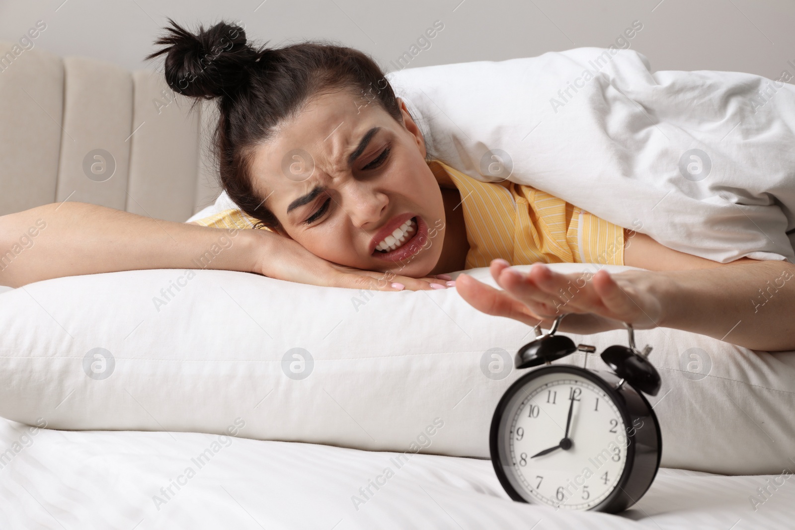 Photo of Emotional overslept woman with alarm clock in bed. Being late concept