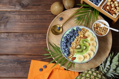 Photo of Tasty smoothie bowl with fresh fruits and oatmeal served on wooden table, flat lay. Space for text