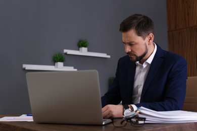 Businessman working with laptop and documents at table in office