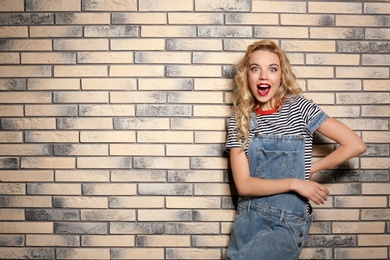 Photo of Emotional stylish young woman on brick wall background