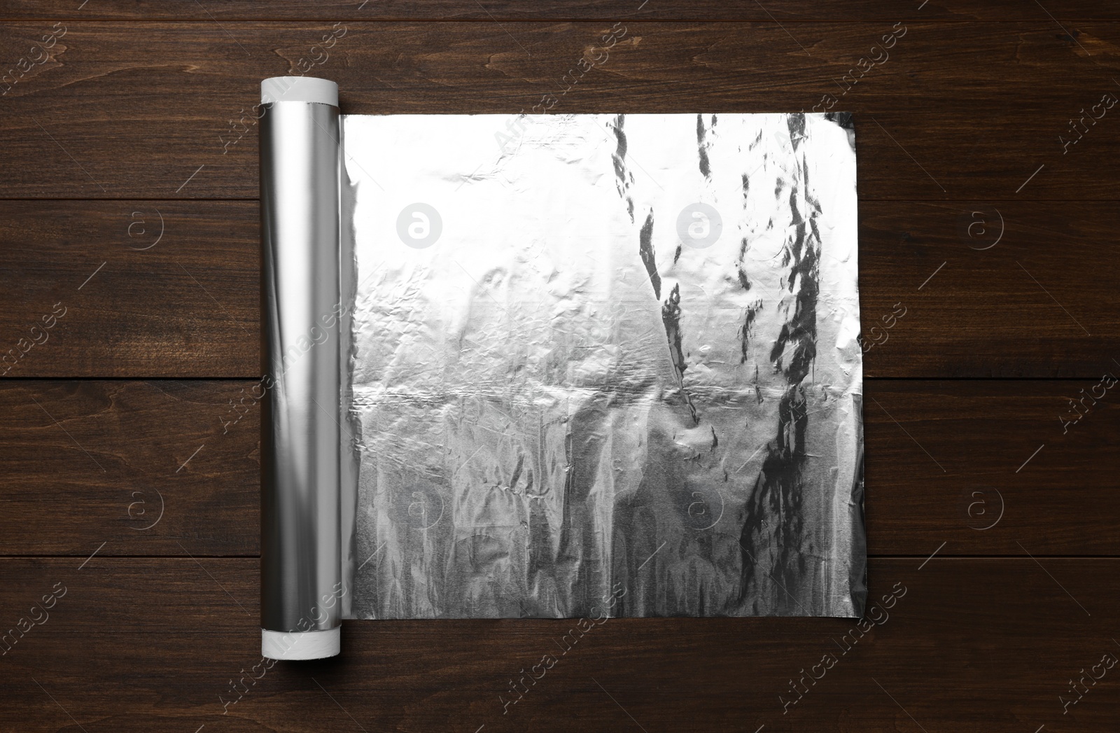 Photo of Roll of foil paper on wooden table, top view