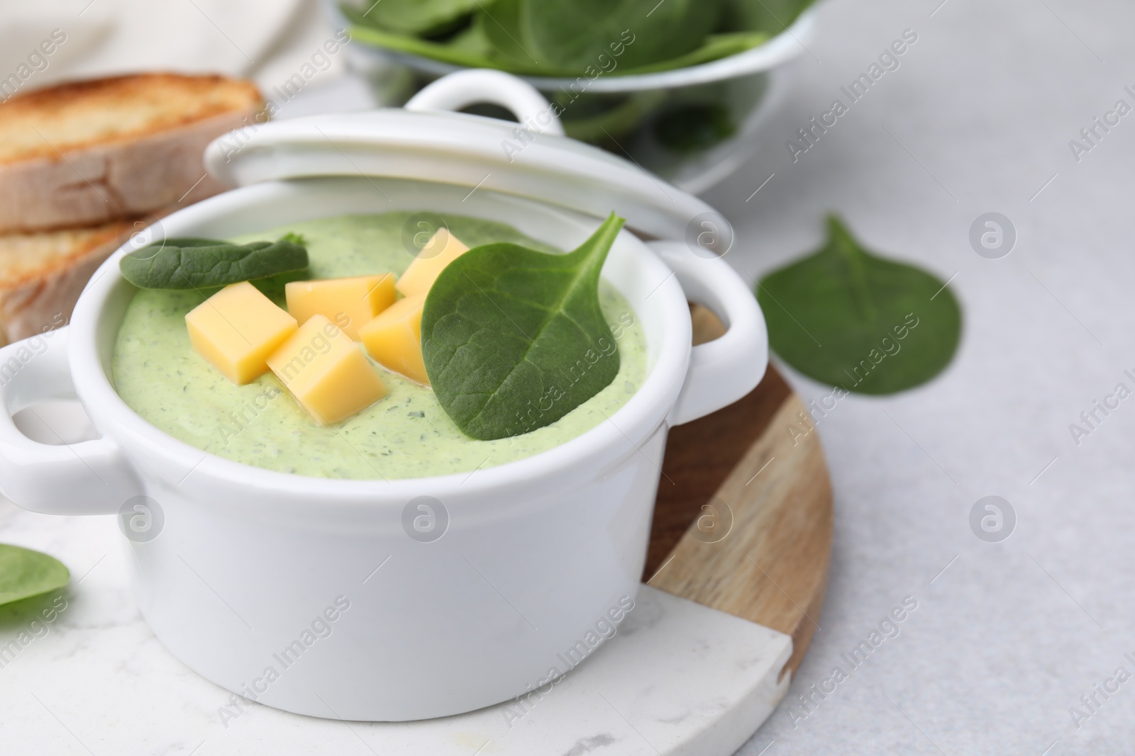 Photo of Delicious spinach cream soup with cheese in bowl on light grey table. Space for text