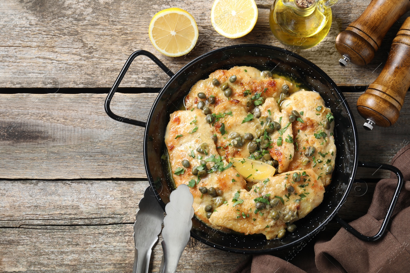 Photo of Delicious chicken piccata with herbs and lemon on wooden table, flat lay. Space for text