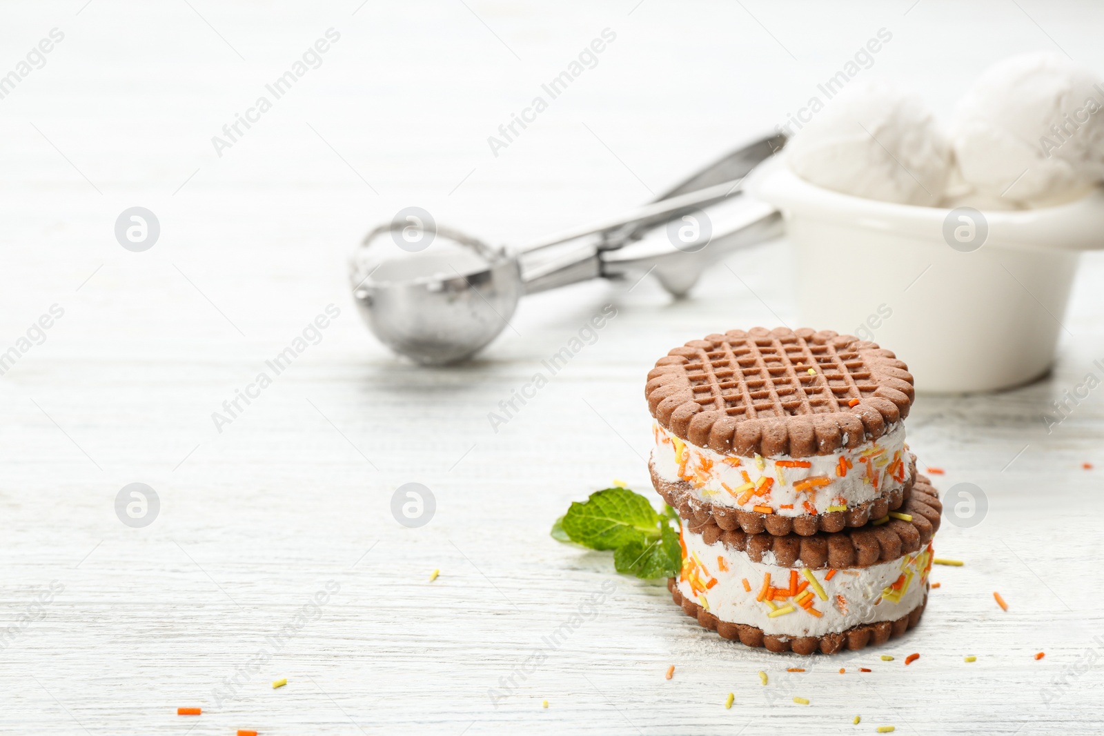 Photo of Sweet delicious ice cream cookie sandwiches on white wooden table. Space for text