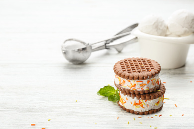 Photo of Sweet delicious ice cream cookie sandwiches on white wooden table. Space for text