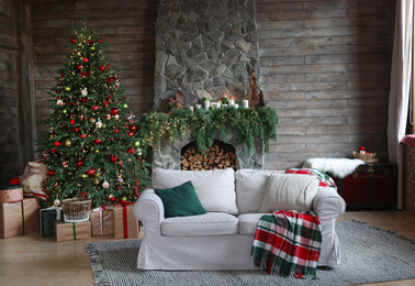 Photo of Festive interior with comfortable sofa and decorated Christmas tree