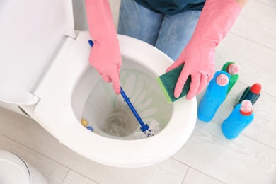 Photo of Woman cleaning toilet bowl in bathroom