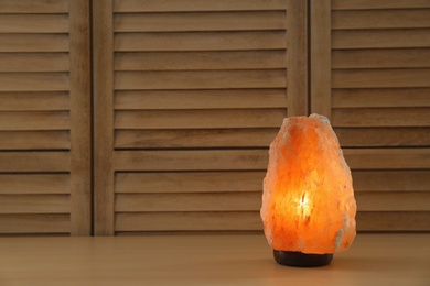 Photo of Himalayan salt lamp and space for text on wooden background