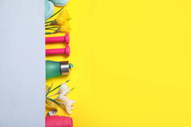 Photo of Flat lay composition with spring flowers and sports items on yellow background. Space for text