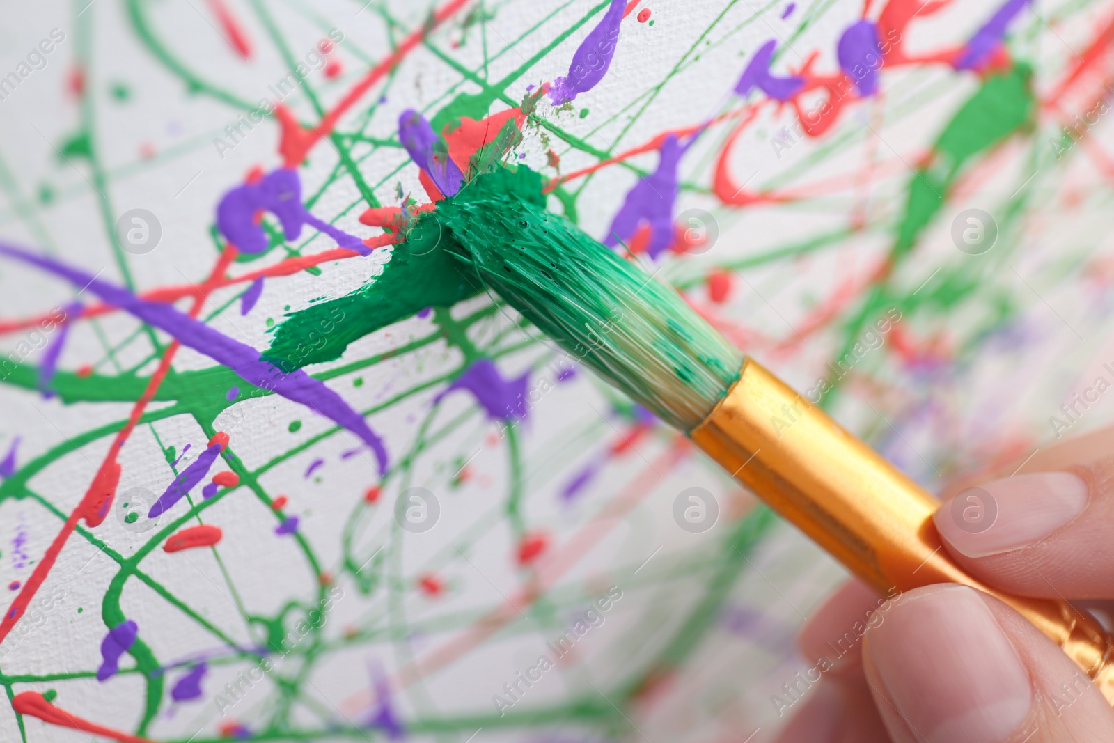 Photo of Artist painting on canvas with brush, closeup