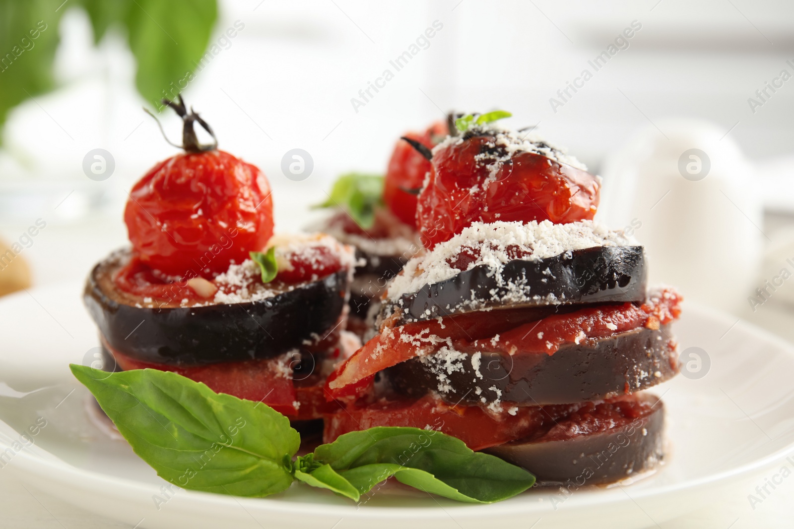 Photo of Baked eggplant with tomatoes, cheese and basil served on kitchen table, closeup