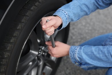 Young man changing tire of car on roadside, closeup