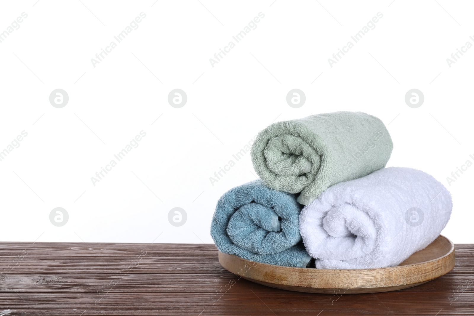 Photo of Fresh towels on wooden table against white background. Space for text