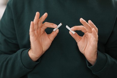 Photo of Stop smoking concept. Man holding pieces of broken cigarette, closeup