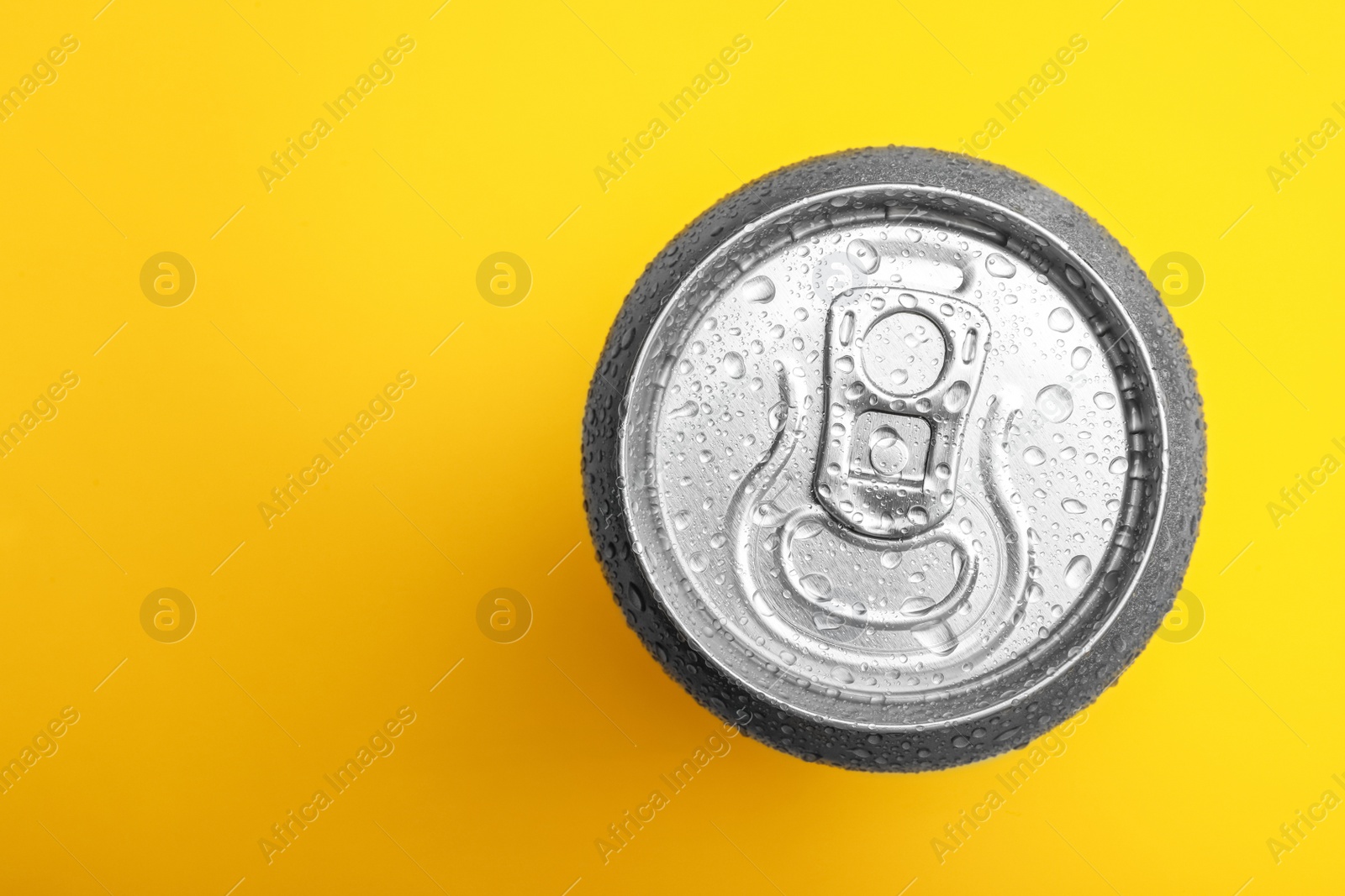 Photo of Wet closed can on yellow background, top view. Space for text