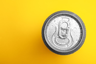 Photo of Wet closed can on yellow background, top view. Space for text