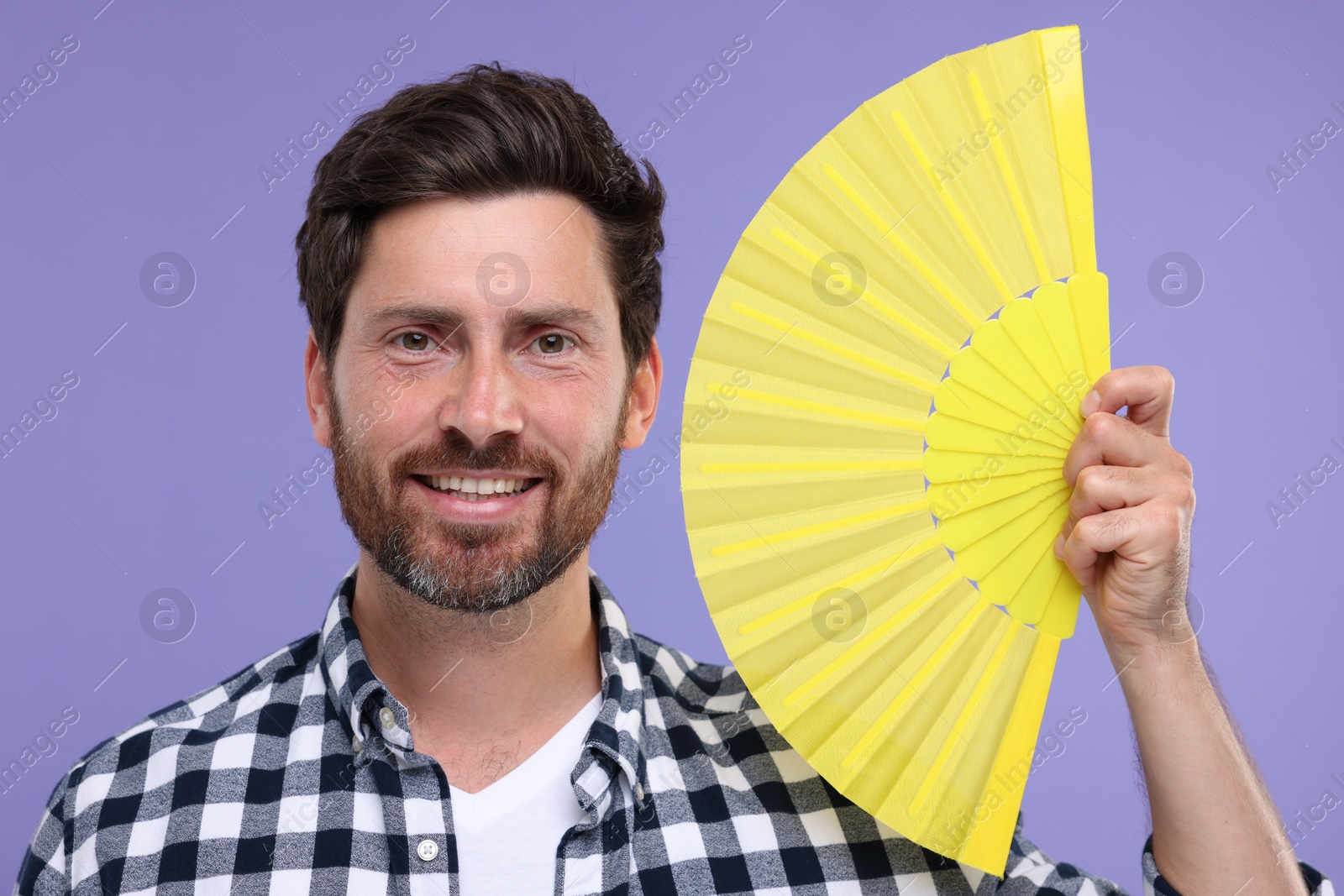 Photo of Happy man holding hand fan on purple background