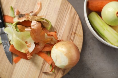 Photo of Peels of fresh vegetables and knife on grey table, flat lay