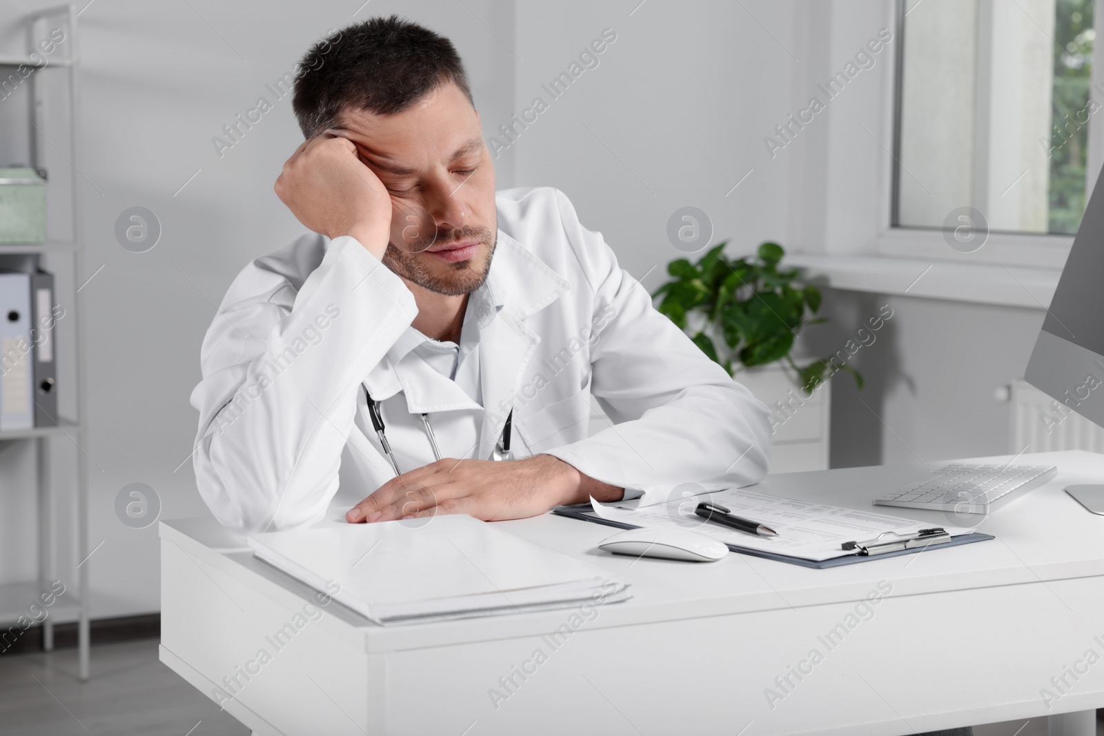 Photo of Exhausted doctor sleeping at workplace in hospital