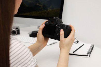 Photographer with camera at white table indoors, closeup