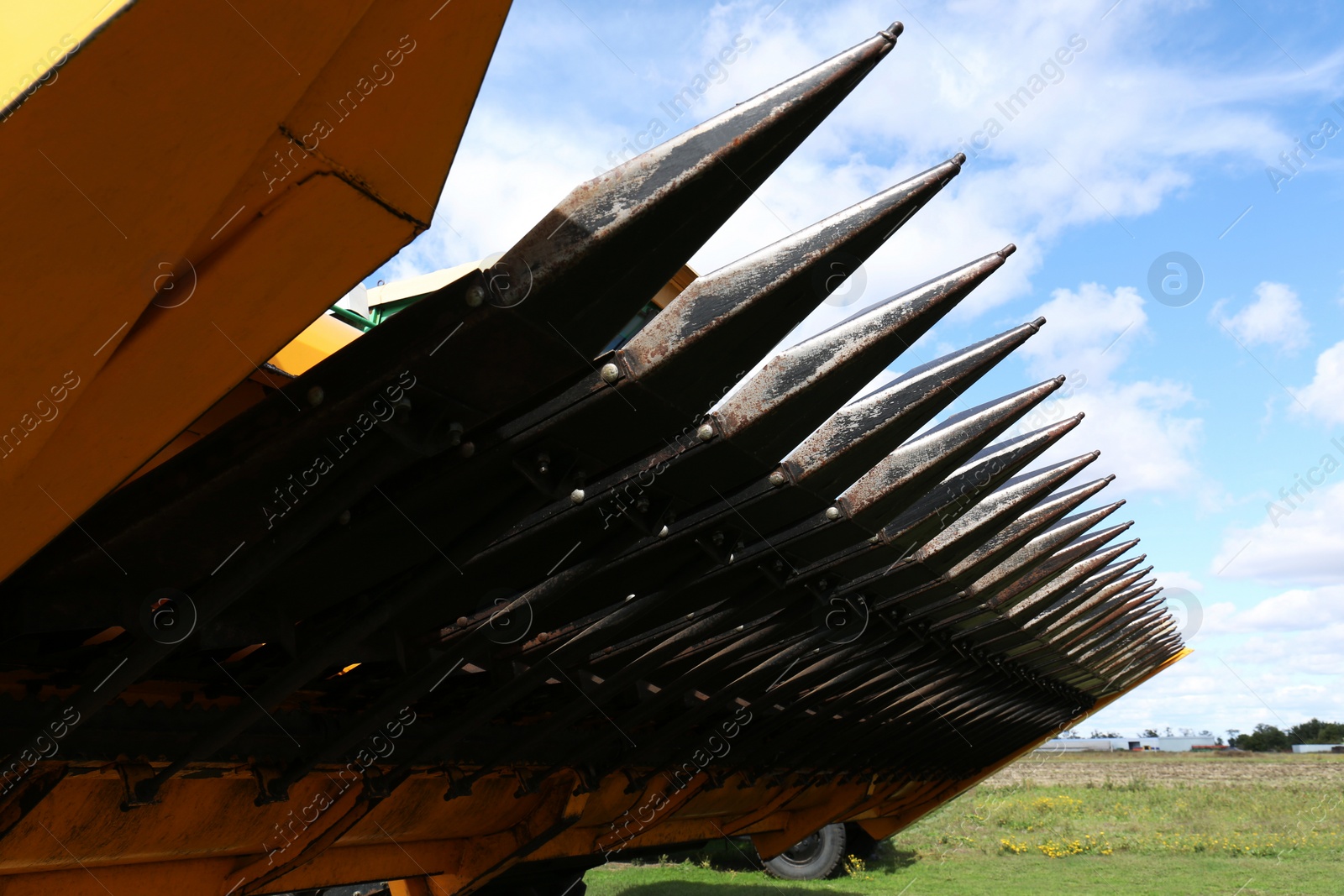 Photo of Modern combine harvester against blue sky with clouds, closeup