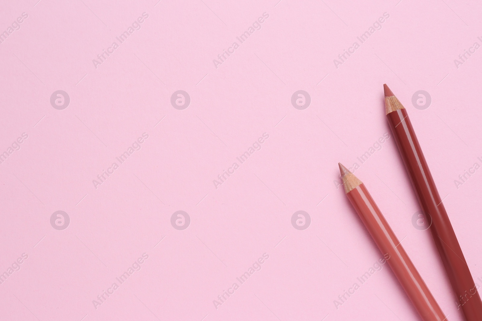 Photo of Lip pencils on pink background, flat lay with space for text. Cosmetic product