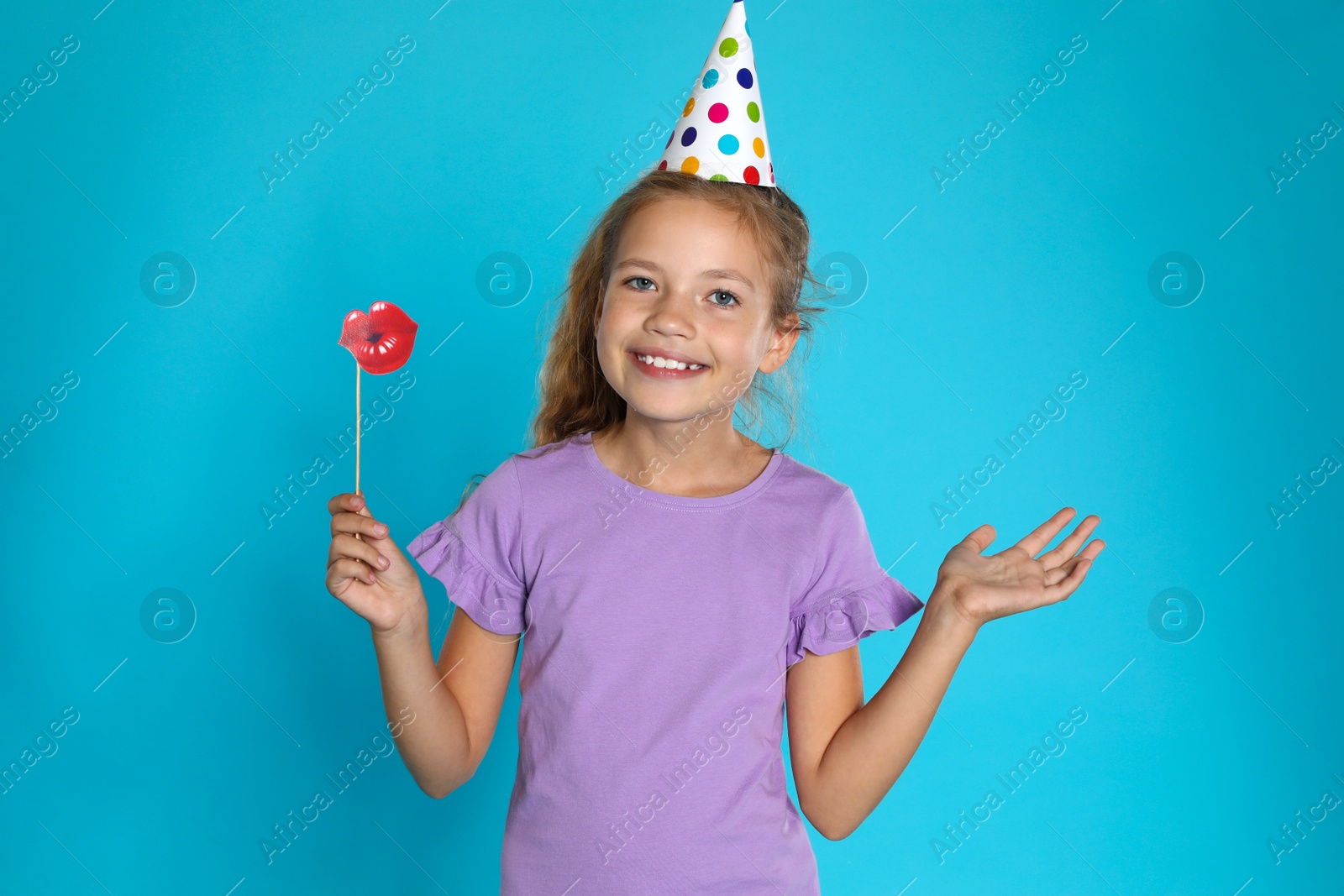 Photo of Happy girl with photo booth props on blue background. Birthday celebration