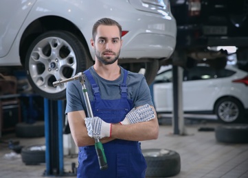 Photo of Young mechanic with torque wrench at tire service