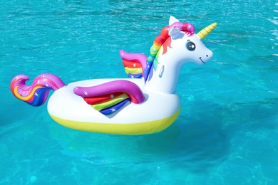 Photo of Funny inflatable unicorn ring floating in swimming pool on sunny day