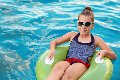 Photo of Happy little girl on inflatable ring in swimming pool