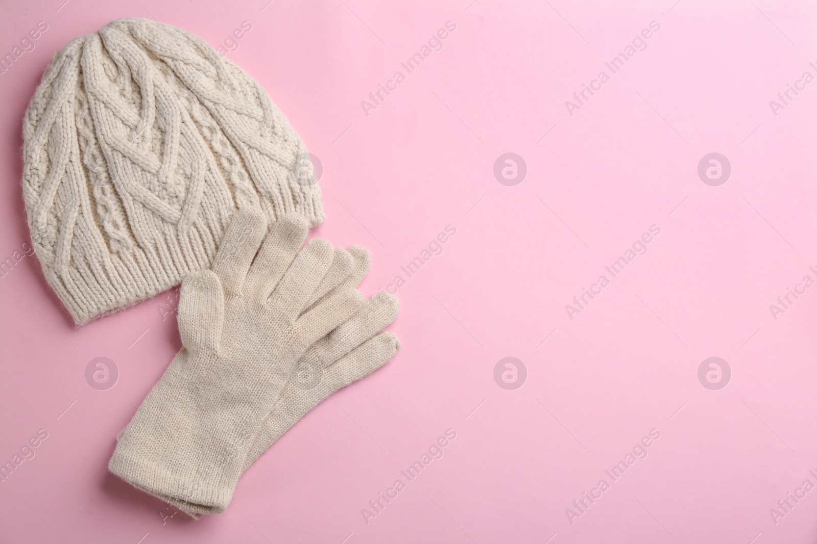 Photo of Woolen gloves and hat on pink background, flat lay. Space for text