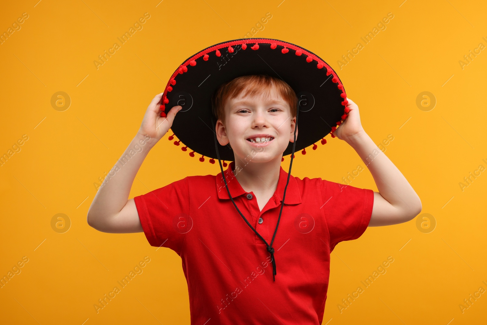 Photo of Cute boy in Mexican sombrero hat on yellow background