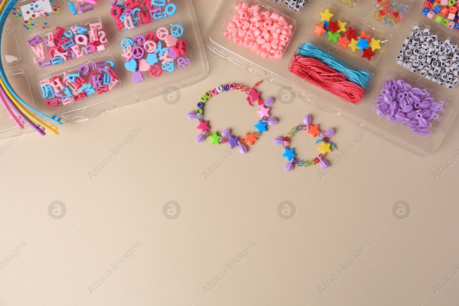 Photo of Handmade jewelry kit for kids. Colorful beads, wristbands and bracelets on beige background, flat lay. Space for text