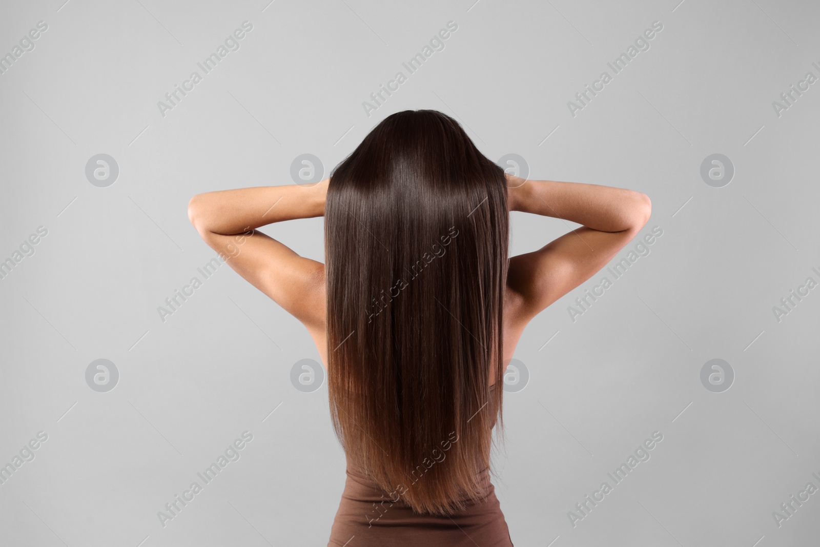 Photo of Hair styling. Woman with straight long hair on grey background, back view