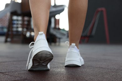 Woman walking in stylish sneakers outdoors, closeup