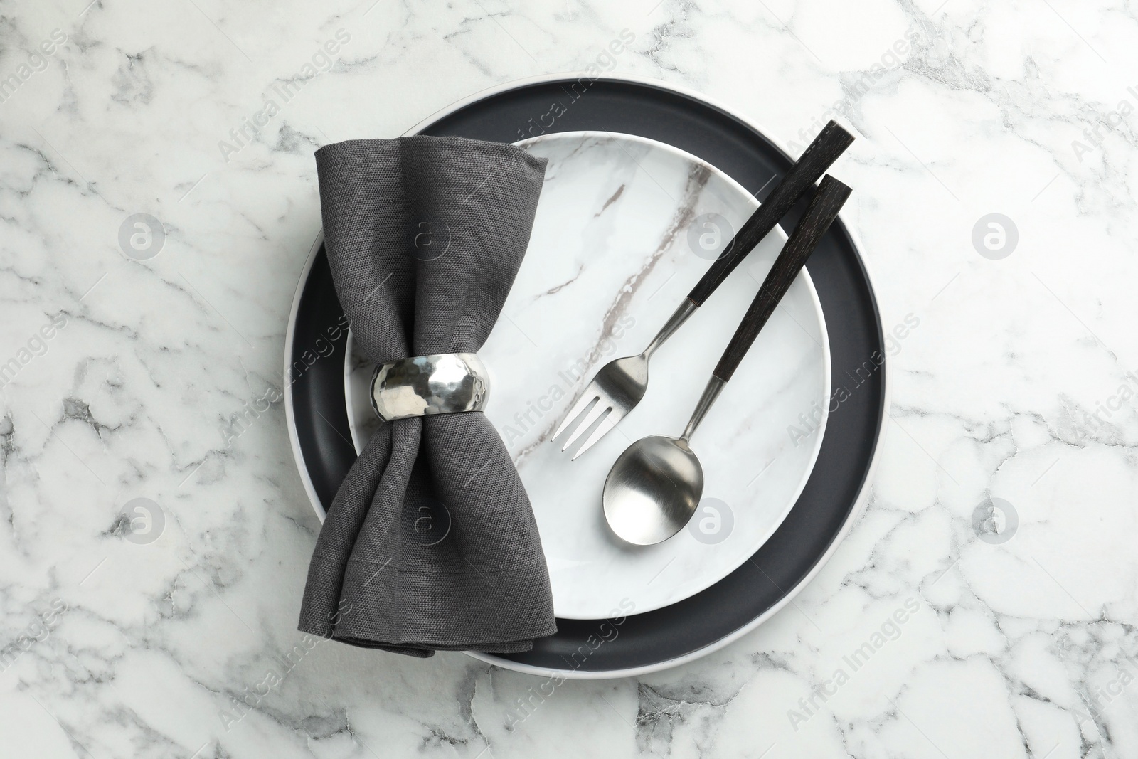 Photo of Stylish setting with cutlery, napkin and plates on white marble table, top view