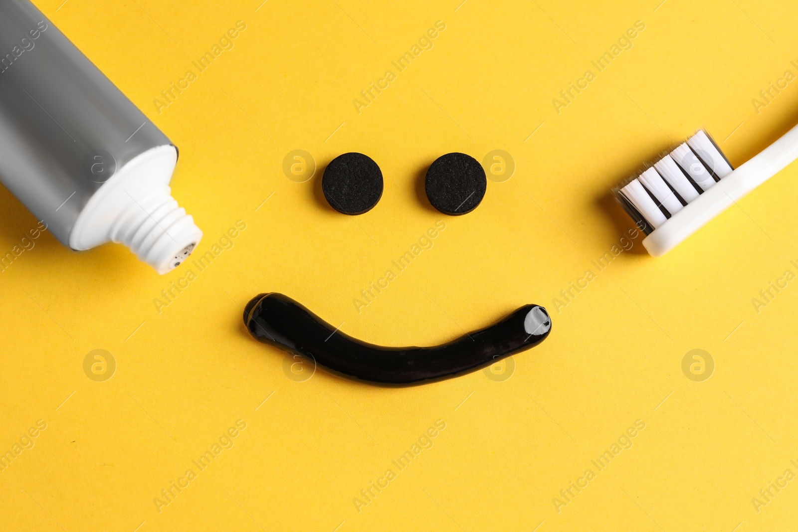 Photo of Flat lay composition with charcoal toothpaste on yellow background